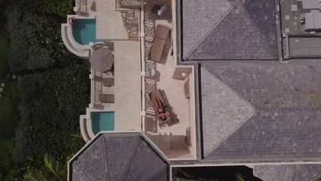 Aerial-rise-up-view-of-a-woman-model-relaxing-on-a-porch-or-deck-of-a-luxury-resort-hotel-or-condo-in-Barbados-Caribbean