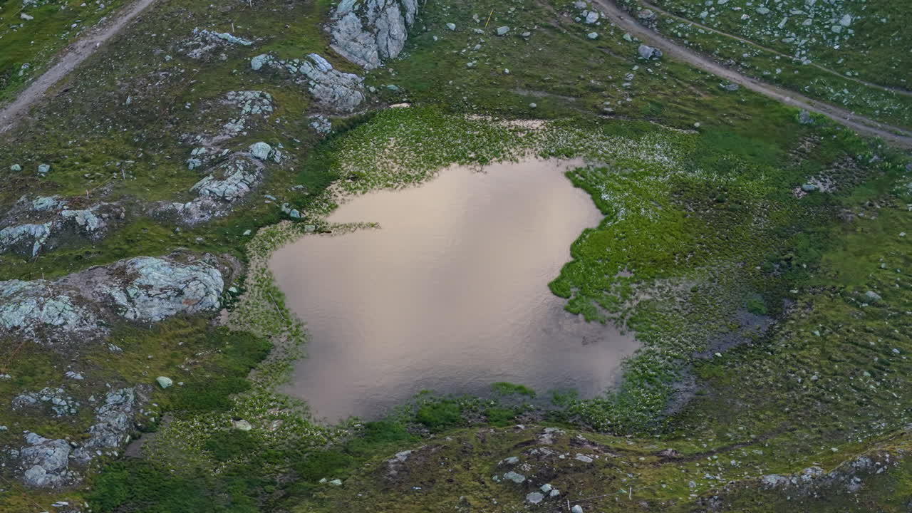 Aerial view of serene lake in Swiss Alps with rocks and greenery