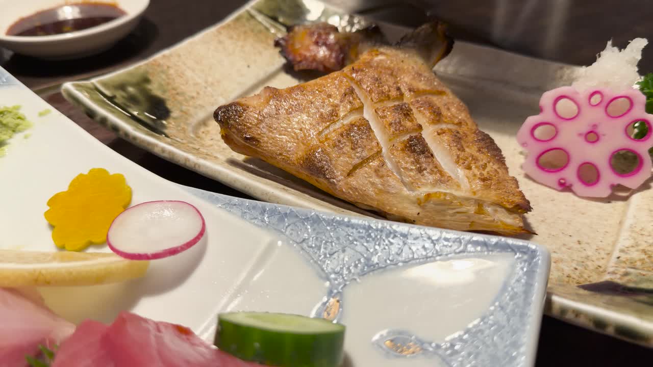 Grilled fish garnished with lemon, pickled vegetables, and radish in warm, ambient restaurant lighting