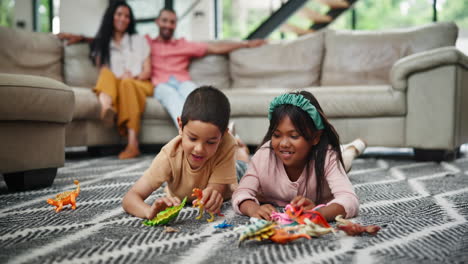 happy siblings playing with dinosaurs at home