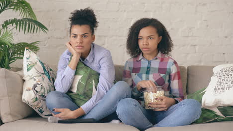 two friends watching a movie at home