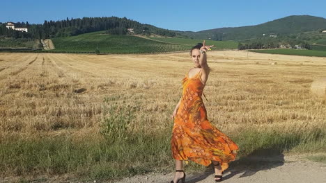 joven morena caminando en un campo de trigo a principios de verano mientras canta