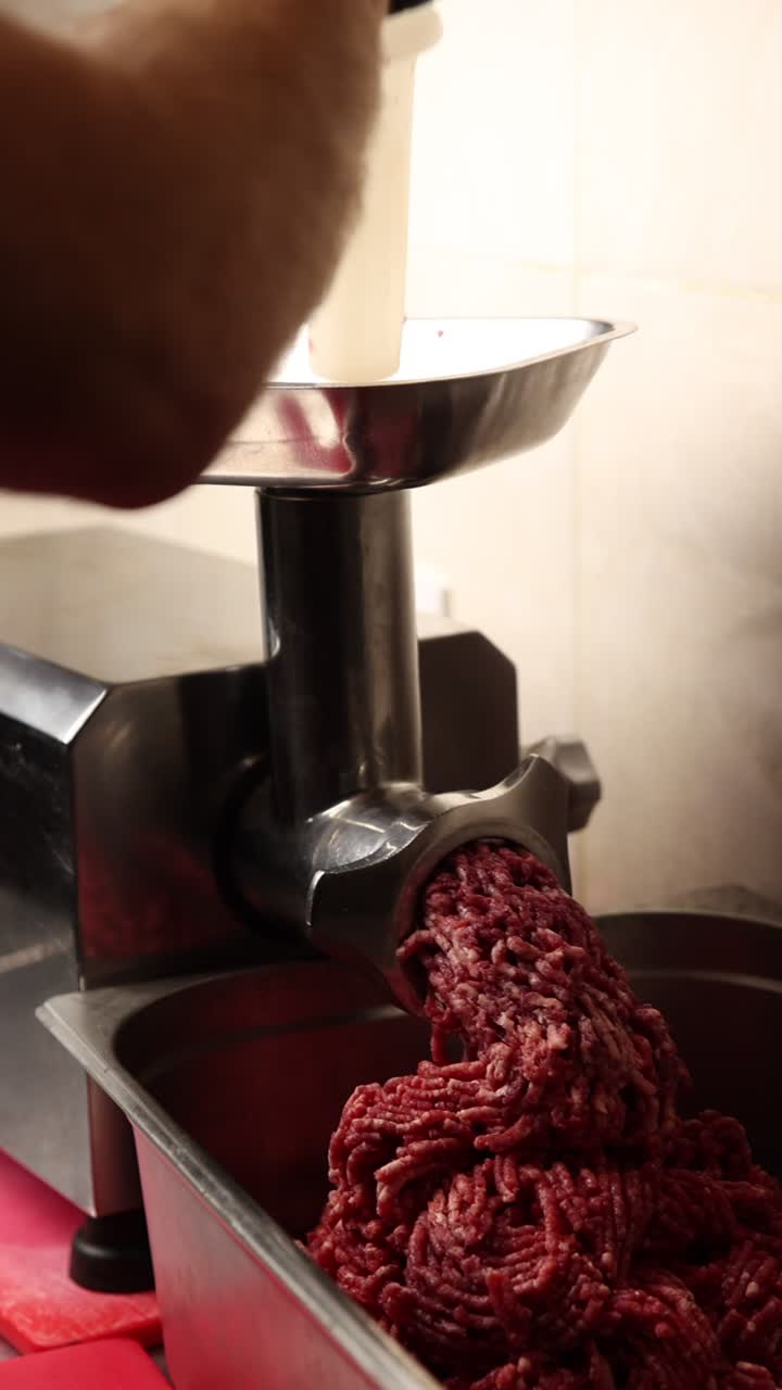 Primo piano di un tritacarne che produce carne macinata fresca in una cucina