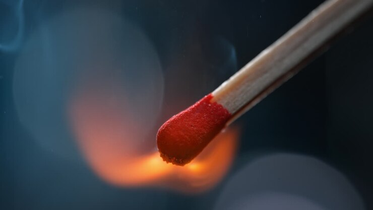 Igniting Match In Macro And Slow Motion - Red Head Combusts And Emits Smoke on the Dark Blue Background