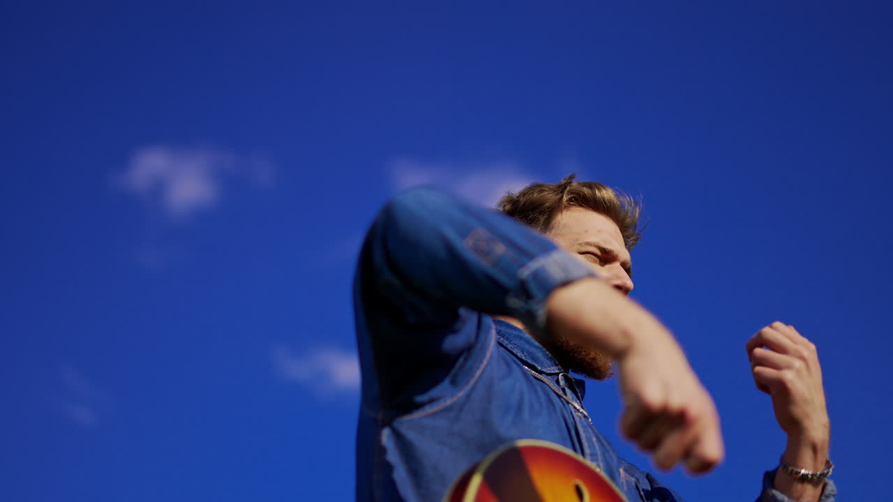 Man playing guitar under a blue sky