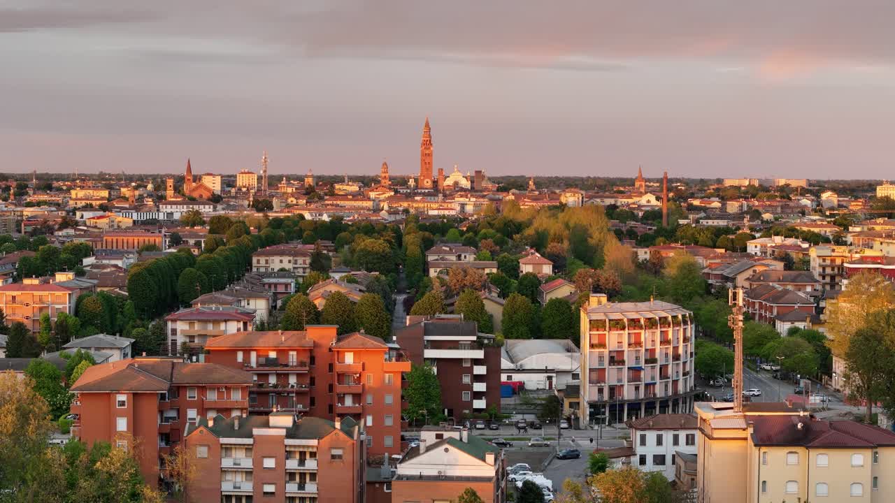 Static drone view of Cremona, Italy, highlighting the Torrazzo bell tower, Santa Maria Assunta Cathedral, and surrounding churches, framed by tree-lined streets and residential buildings in Lombardy