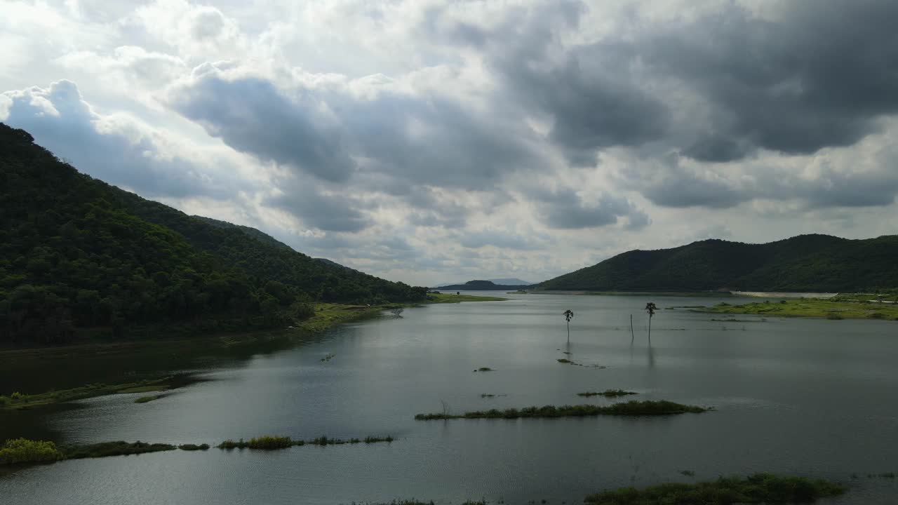Aerial footage sliding to the right revealing a truck at the lake, this gorgeous scenery, rainclouds reflected on water, mountains; Saraburi, Thailand