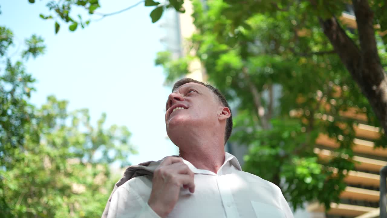 CEO of businessman looking up to the nature tree sky sunlight, concept of business working with vision freedom and successful, urban city lifestyle with natural environment, slow-motion shot