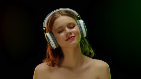 young woman enjoying music with headphones in colored light