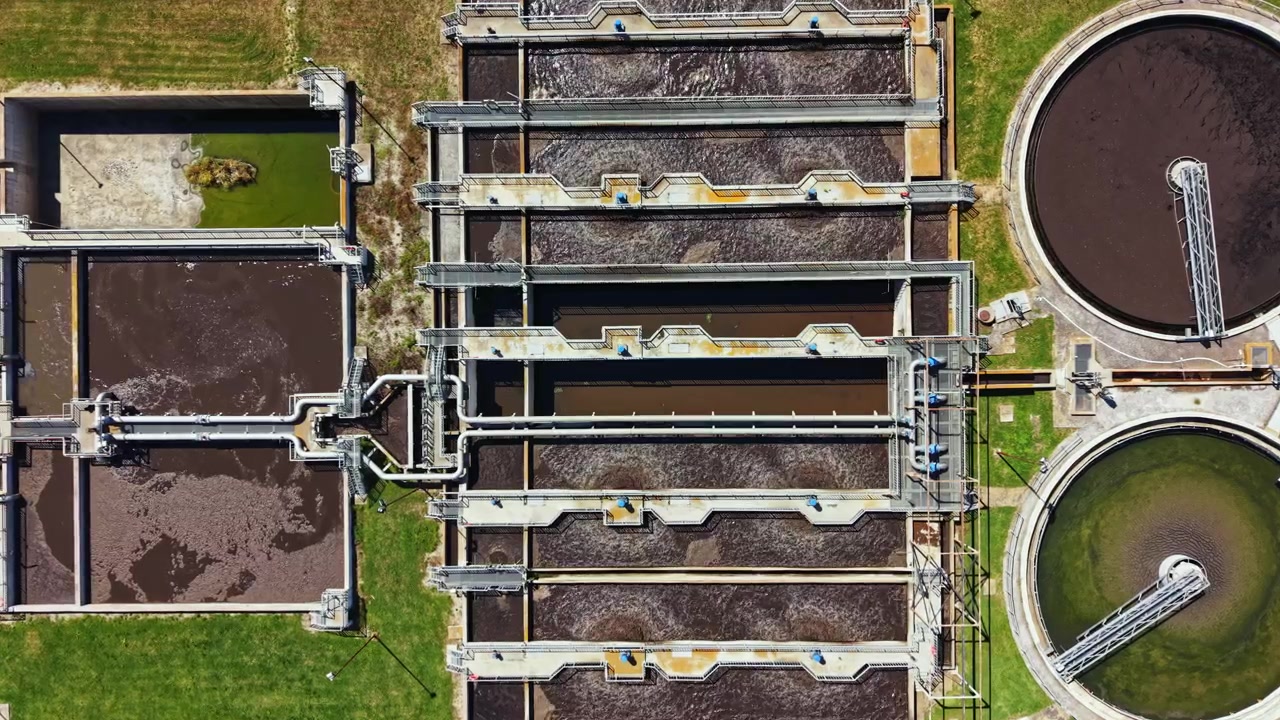 Water treatment facility in operation with multiple large tanks and machinery for cleaning wastewater at midday