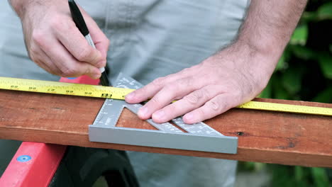 carpenter prepares wood for woodworking project, slow motion taking of measurements on wood plank