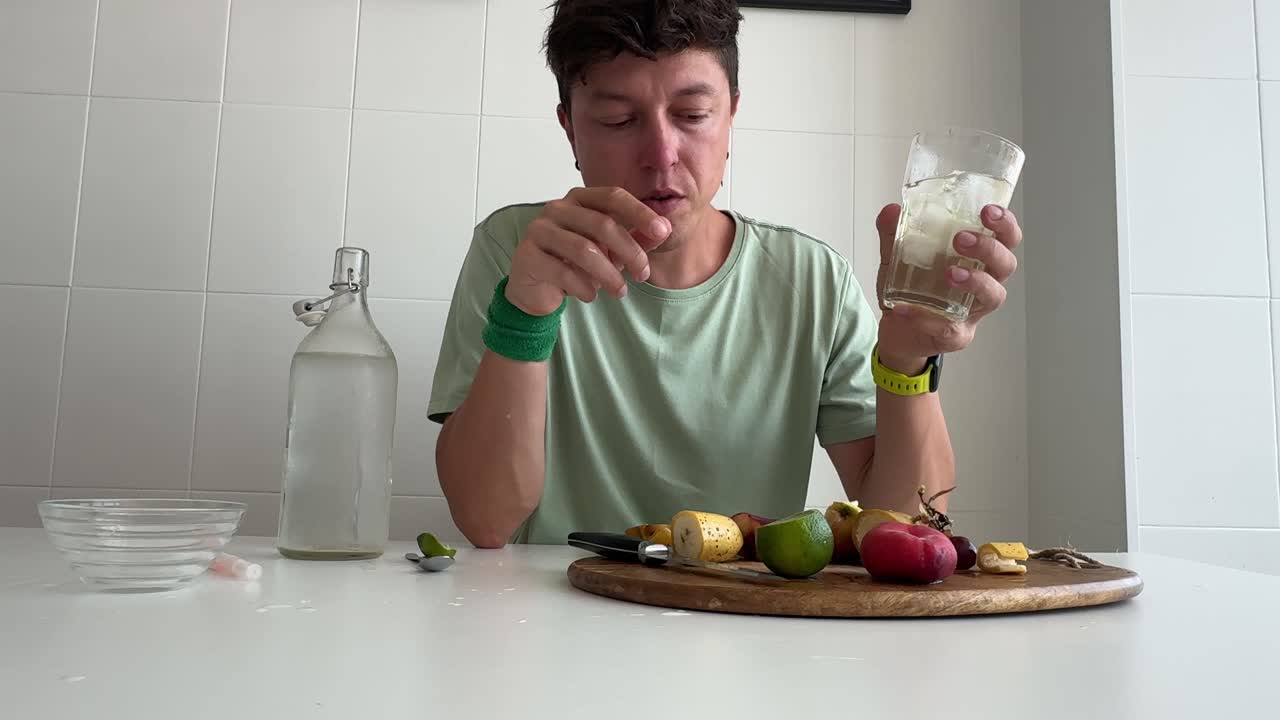 Uomo che mangia frutta fresca e beve acqua a un tavolo
