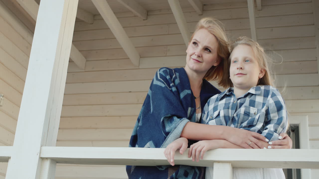 엄마와 딸이 시골집 테라스에 서 있다