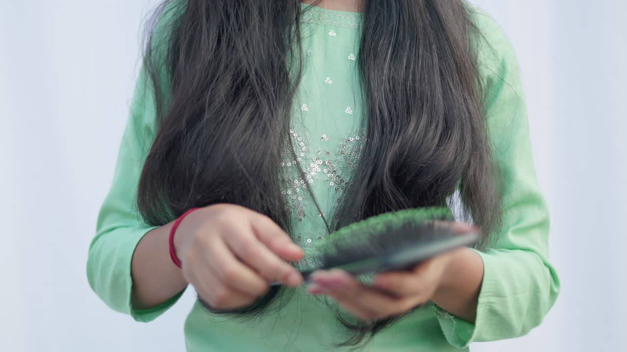 crop view shot of a woman coming her hair with a brush and removes large amount of fallen hair from the brush, hairloss, androgenic alopecia, close up shot.