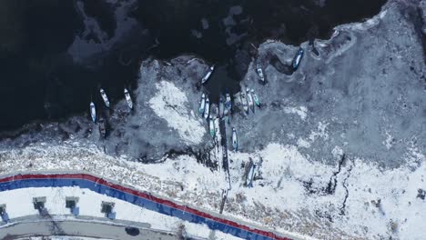 aerial shot of frozen lake and boats from the top