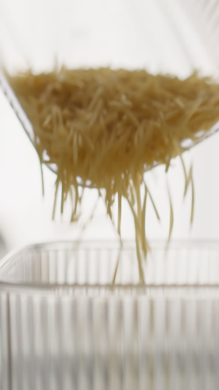 persona vierte espagueti corto roto en un recipiente de plástico conveniente para medir la porción. preparación para cocinar en una cocina ligera y acogedora. almacenamiento de productos crudos