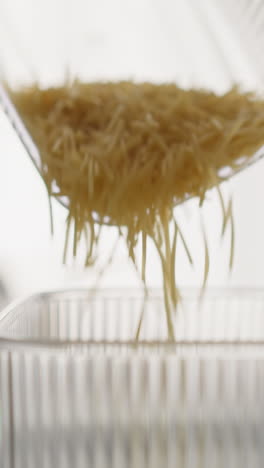 pouring dry pasta into container