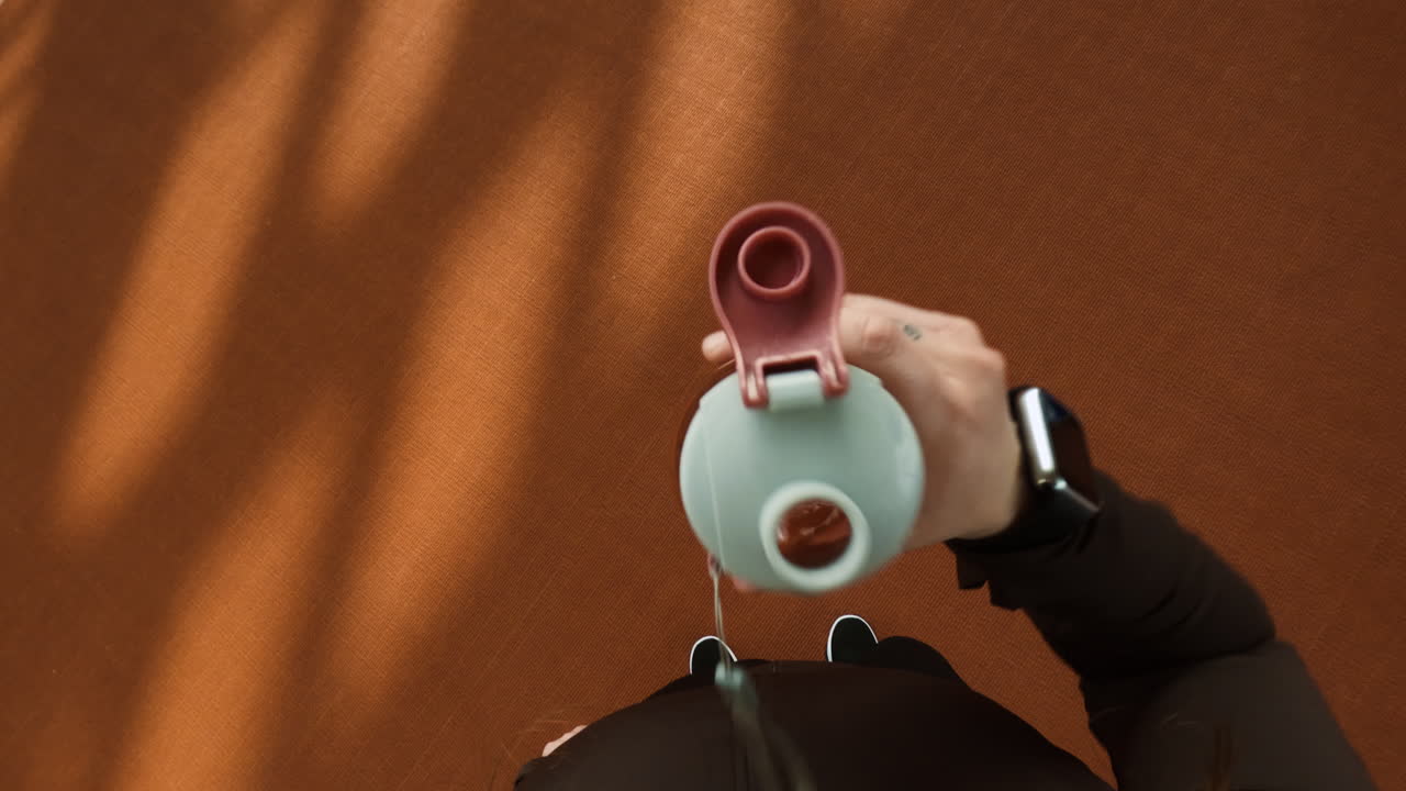 Person holding a water bottle on a sports track, overhead view