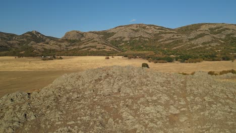 Fly-Over-Rocky-Slopes-With-Mountain-Ridges-In-The-Background