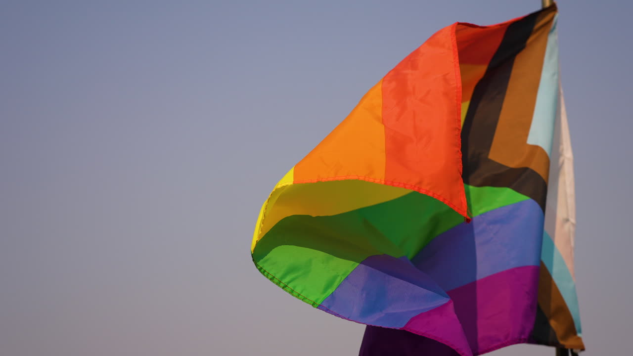 disparo en cámara lenta del arco iris bandera lgbtq+ soplando en el viento en la playa de canon