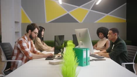 multinational people sit at desks working on computers