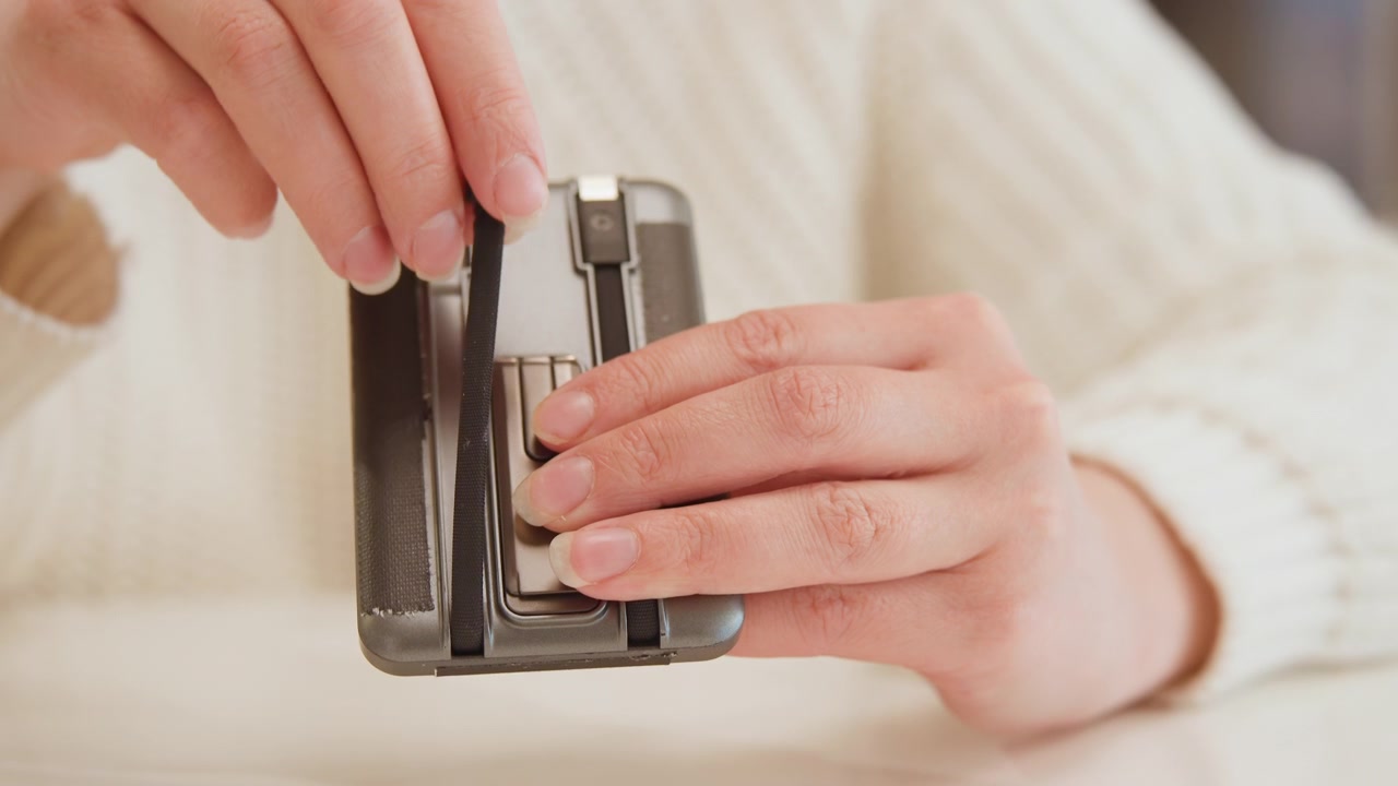 Close view of hands inserting textured plastic cartridge into compact camera back, fingers guiding alignment and steady thumb pressure for careful loading in soft indoor light, with hand, cartridge