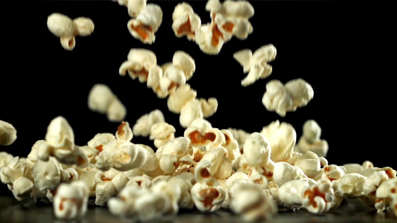 Popcorn che cadono e si posano su una superficie nera al rallentatore
