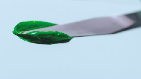 la pintura verde se extiende sobre un lienzo de papel blanco con una espátula