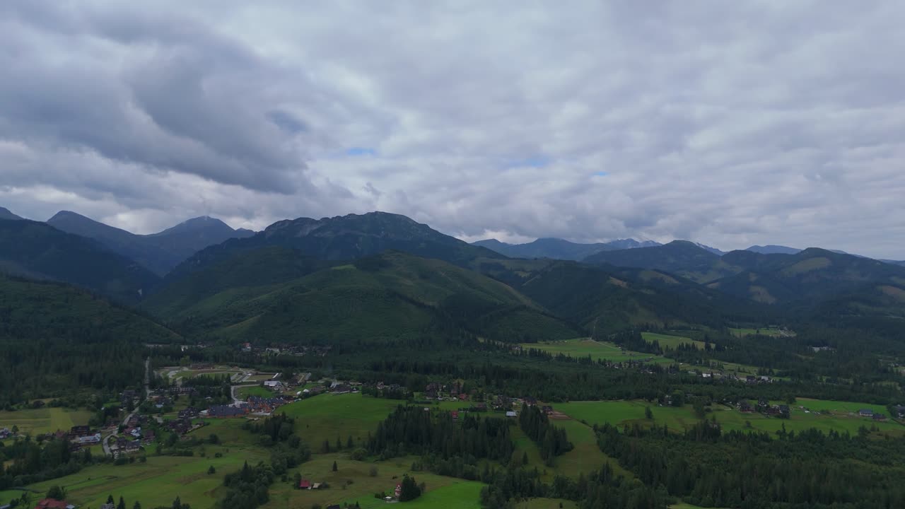 Aerial footage of mountain peaks near Zakopane, Poland, in summer. Lush green landscape with drifting clouds over alpine scenery. Ideal for nature, travel, and outdoor visuals