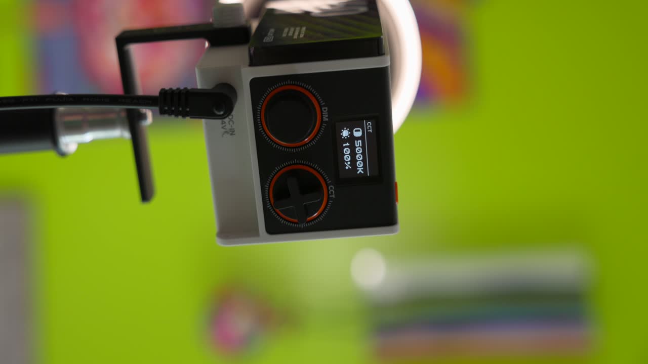 primo piano di un controller di luce video professionistico a tecnologia zhiyun con display e quadranti, montato su un supporto, su uno sfondo verde vibrante