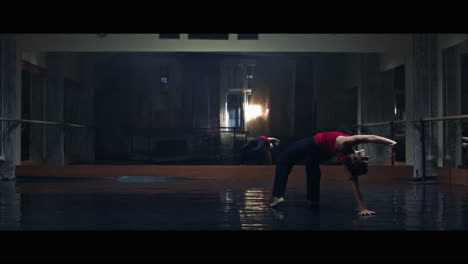 a young woman practices modern dancing and ballet in a moody room full of mirrors
