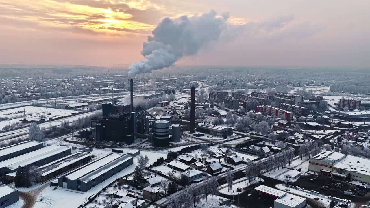 Winter cityscape with snow-covered buildings and industrial structures under soft seasonal light
