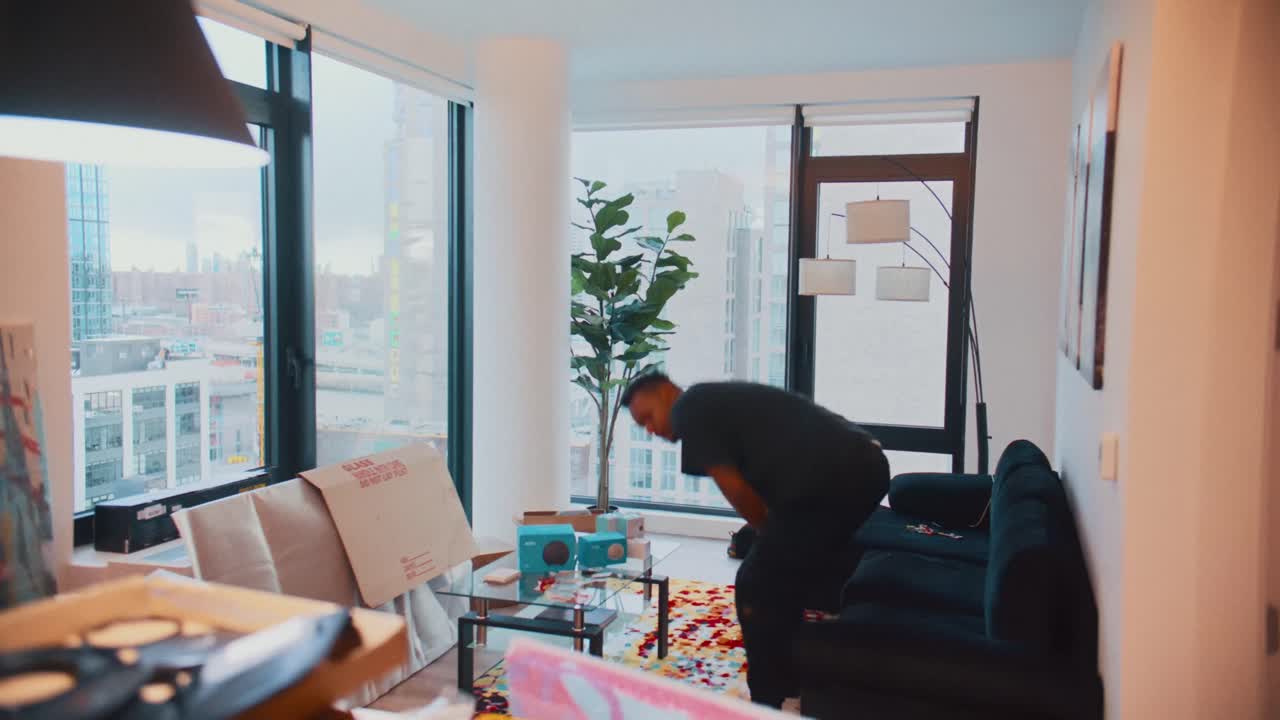 젊은 남자가 도시가 내려다보이는 퇴창이 있는 현대적인 아파트를 리모델링하는 시간 경과