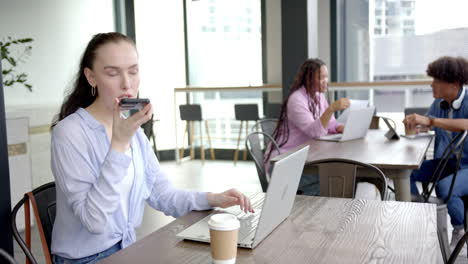using laptop and recording voice message, woman working in modern office space