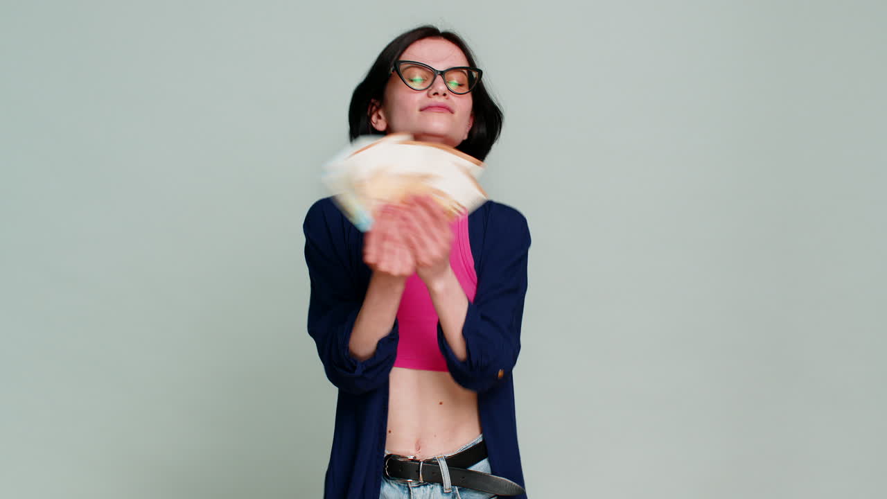 Young woman joyfully dancing holding money euro cash celebrating win financial success happily