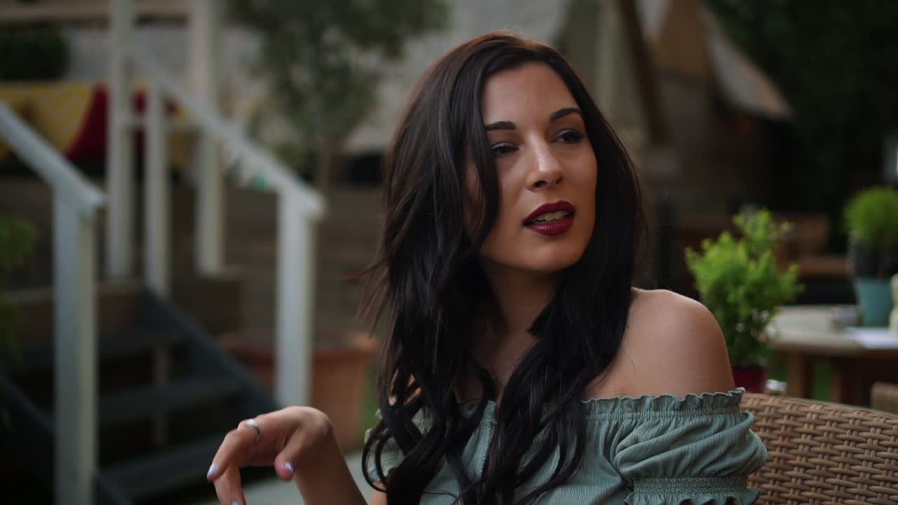 joven morena segura y atractiva con un top informal, usa su teléfono celular, sonríe alegremente a los mensajes de texto, mira a su alrededor