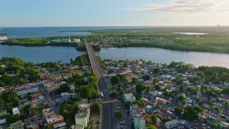 puente aéreo con tráfico sobre el río higuamo en san pedro de macoris durante la puesta de sol - mar del caribe en el fondo