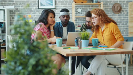 diverse team discussing project on laptop