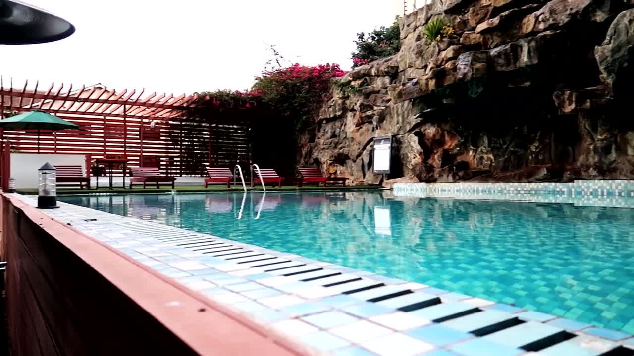Krystalklart blåt vand i en privat pool med liggestole og klippevægge.