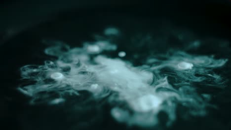 Close-up-of-white-drops-falling-into-dark-green-water