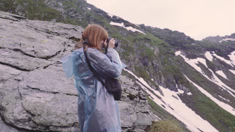 a young woman hiker climbs mountains and photographs landscapes on camera. transfagarasan, carpathian mountains in romania