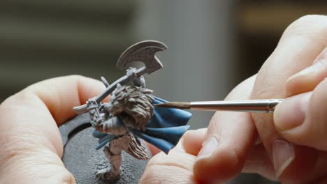 artist male hands painting miniature fantasy figure model delicately with paint brush for role playing game 4k