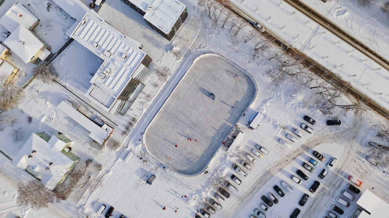 Screwdriver drone shot rotating above a urban ice hockey rink, sunny, winter day