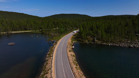 drone following a rv driving road, in middle of arctic lakes of inari, finland