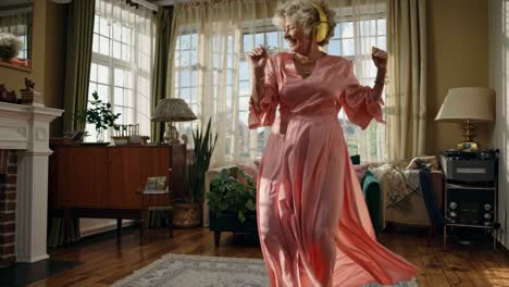 Senior woman in a pink dress dancing in her living room, happy and joyful, medium shot video