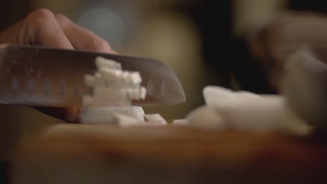 persona cortando cebollas blancas con un cuchillo afilado