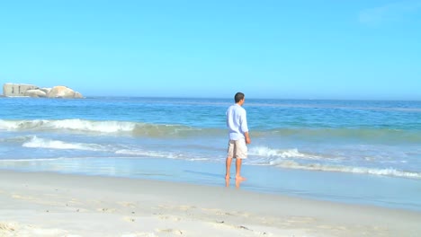 Mann-Blickt-Aufs-Meer,-Während-Er-Seine-Füße-Badet