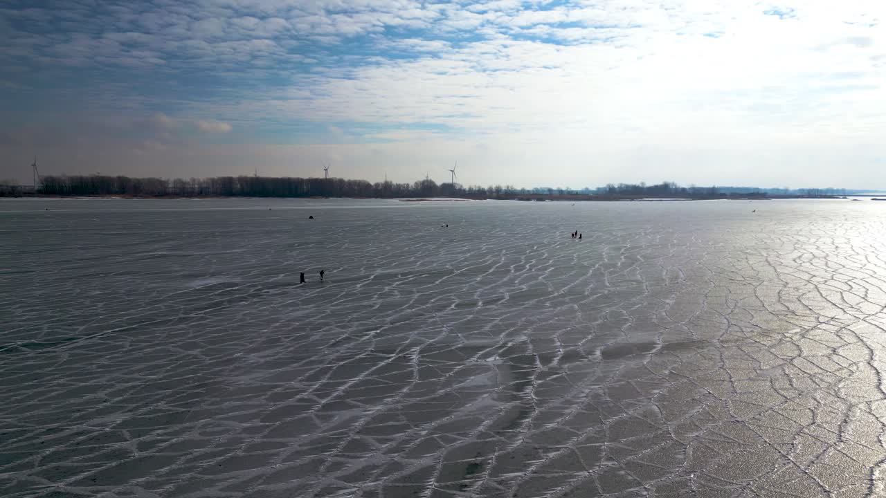 미첼 만의 얼어붙은 호수에서 낚시와 걷기, 배경에 풍차가 있는 세인트 클레어 호수, 60fps 공중 드론 샷