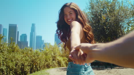 una chica asiática tomando la mano de su novio en el parque. una pareja caminando por la naturaleza.