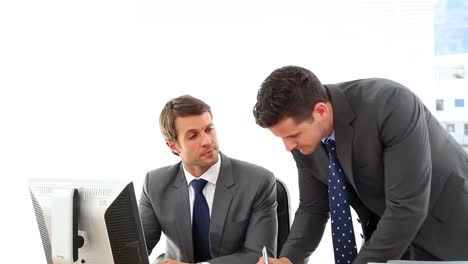 businessmen looking at computer screen talking